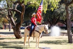 一位骑着六匹白马的人手持美国国旗.